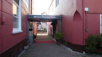 A red building with a reception sign and a paved walkway leading to a door.
