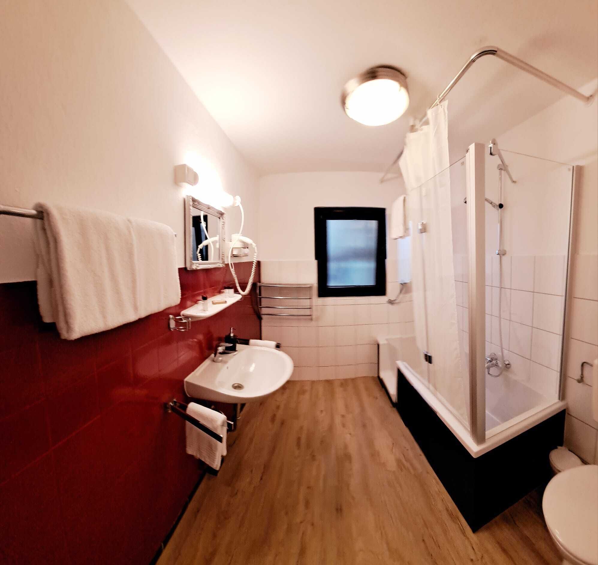 A compact bathroom with a sink, mirror, towel rack, and shower.