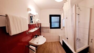 A compact bathroom with a sink, mirror, towel rack, and shower.