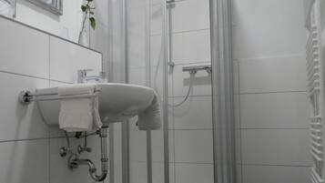 Un baño moderno con inodoro, lavamanos y ducha envuelta en vidrio.
