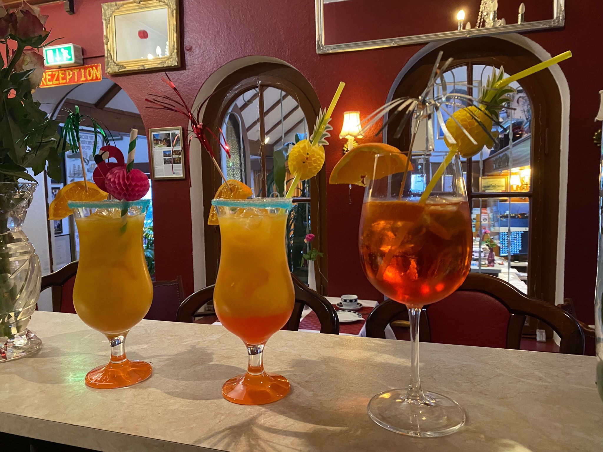 Three drinks on a bar counter with a reception sign above.