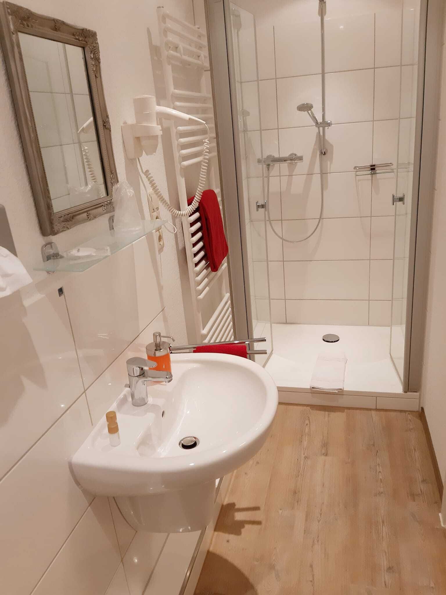 Een moderne badkamer met een witte wastafel, een douchecabine met glas en een glazen douchedeur.
