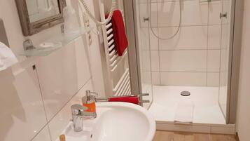 Een moderne badkamer met een witte wastafel, een douchecabine met glas en een glazen douchedeur.