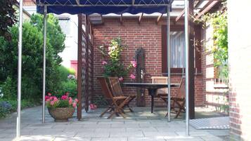 Un patio con mesa y sillas, una pérgola y un muro de ladrillo.
