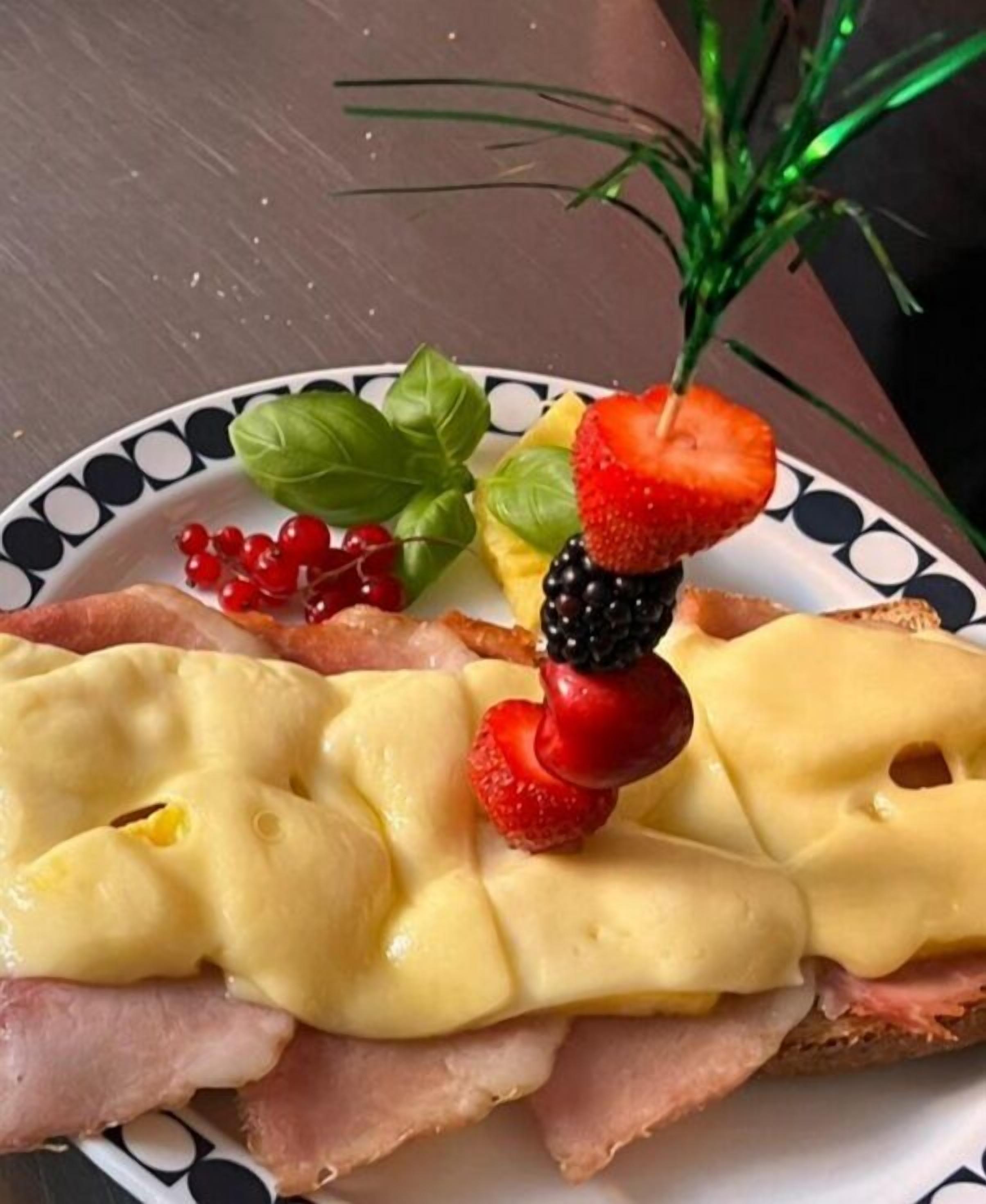 Un piatto con un panino, formaggio e frutta.