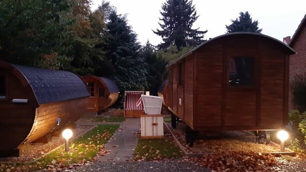 A row of wooden cabins with a pathway leading to a central American flag and a white basket.