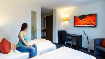 A hotel room with two beds, a desk, a TV, and a chair.