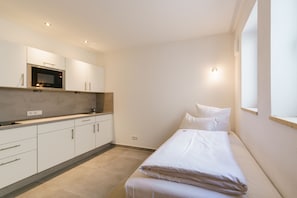 A compact room with a kitchenette, a bed, and a window. - Hotel Duda (Reichertshofen)
