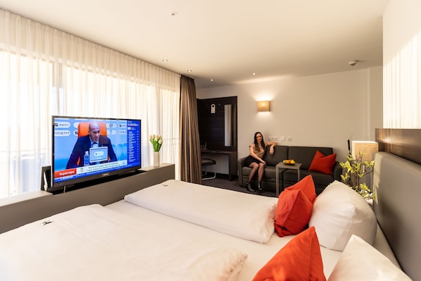 Una habitación de hotel con cama, televisión, sofá y escritorio.