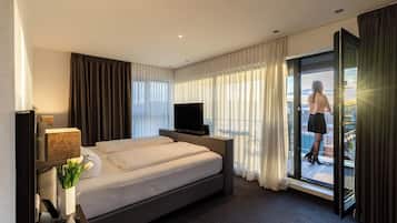 A hotel room with a bed, a TV, a desk, and a balcony with a view.