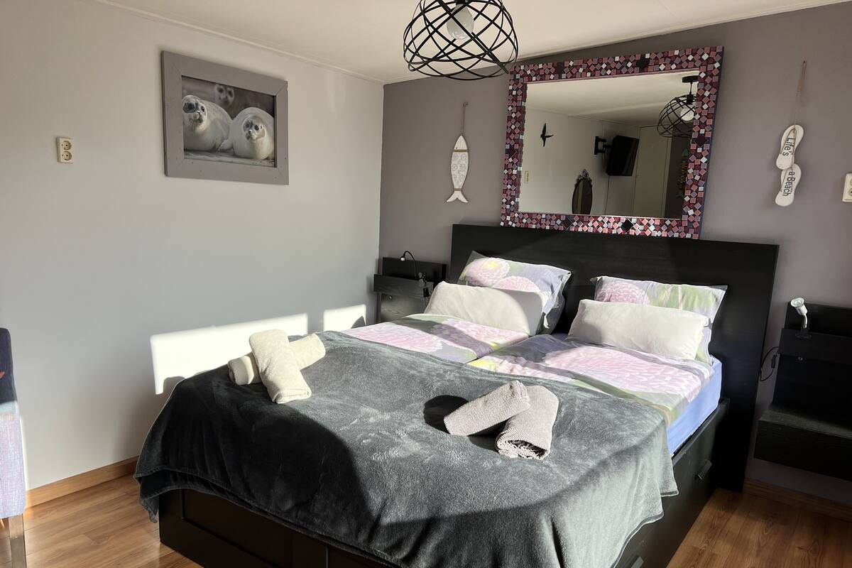Een slaapkamer met een bed, een spiegel, een visdecoratie aan de muur en een handdoek op het bed.