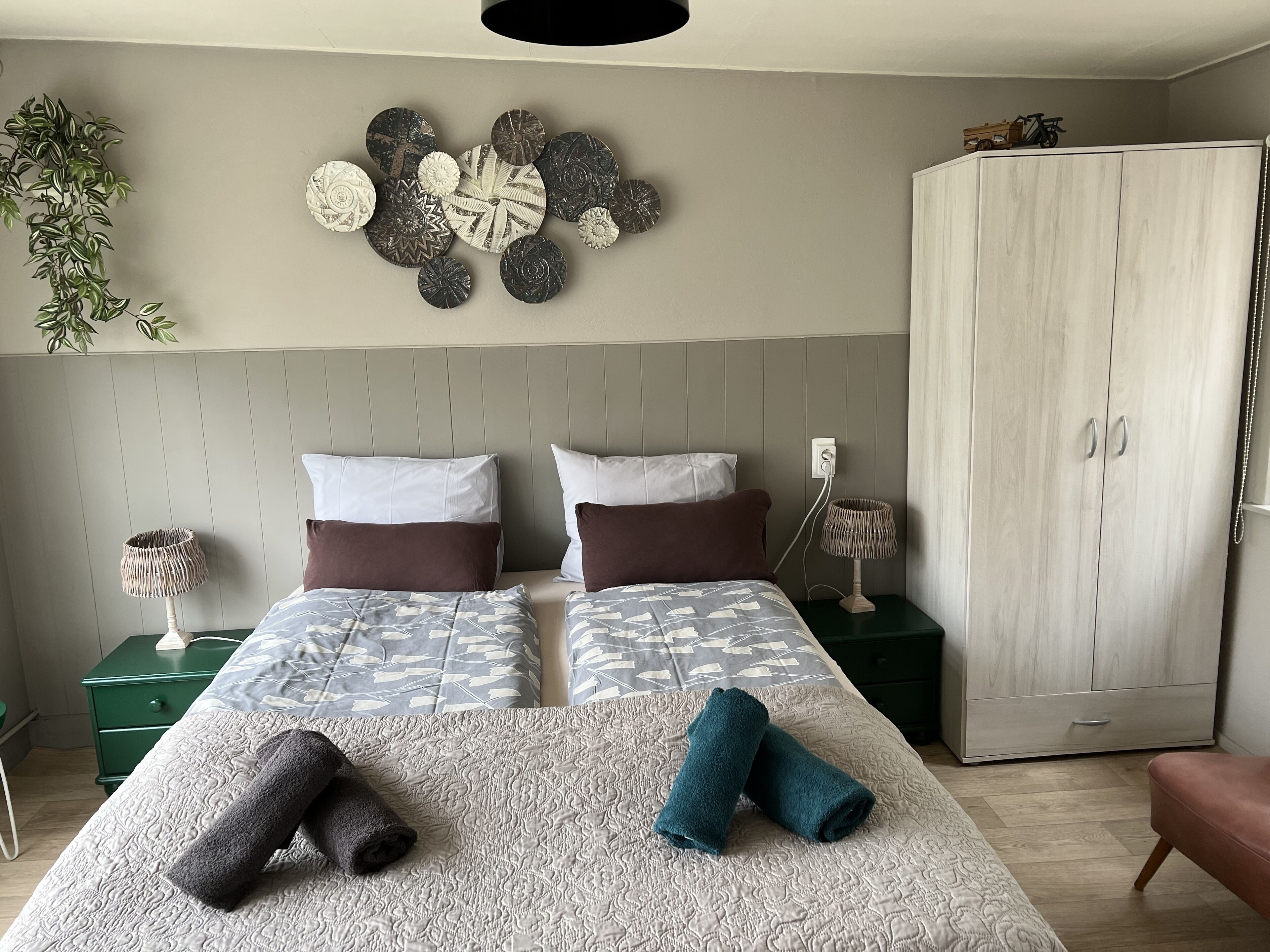 Une chambre à coucher comprenant un lit, deux tables de chevet, une armoire et des éléments de décoration murale.
