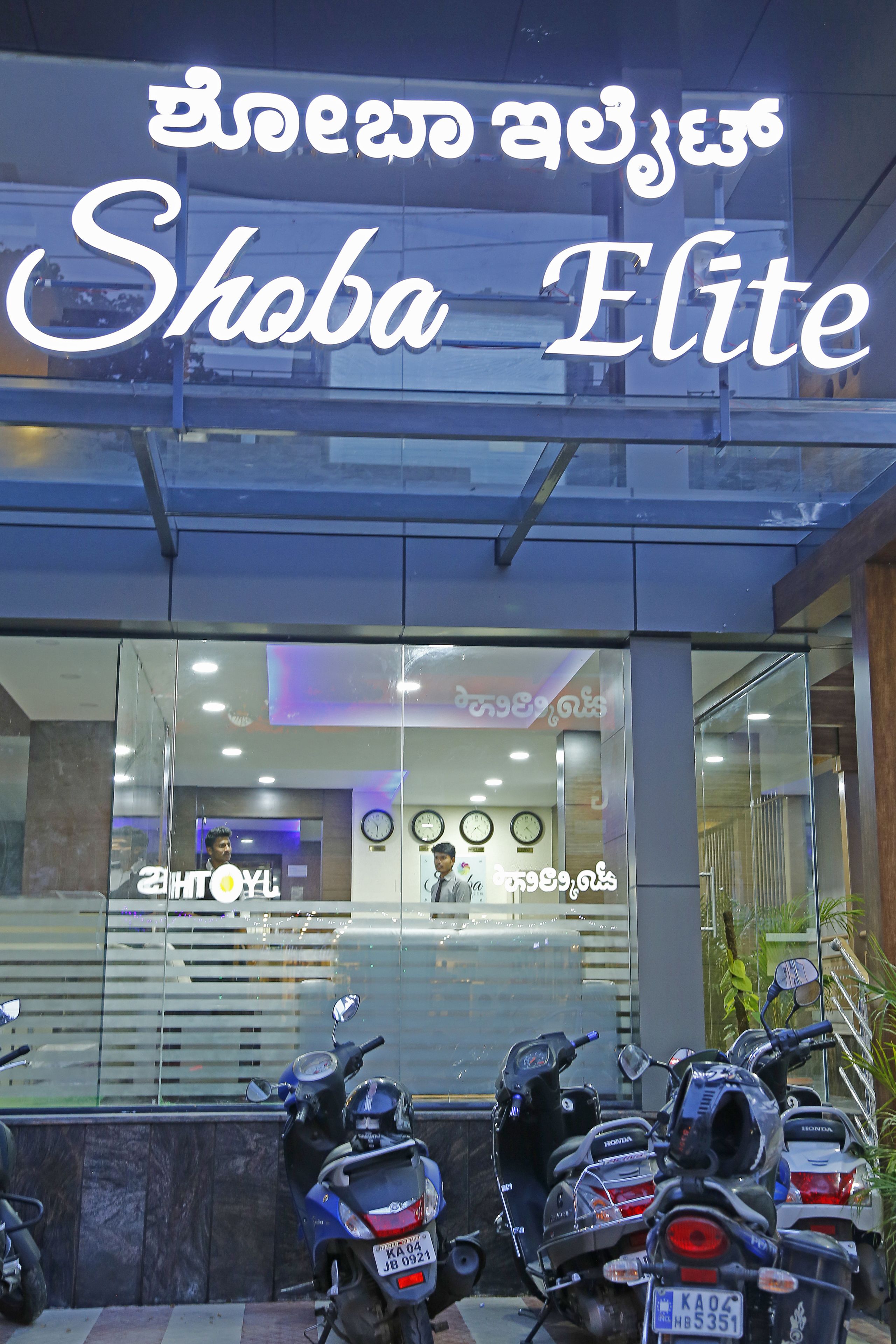 Un edificio con un cartel que dice "Shoba Elite" y varios scooters estacionados.