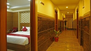 A hotel corridor with a bed, a 'No Smoking' sign, and a potted plant. - Shoba Elite (Bengaluru)