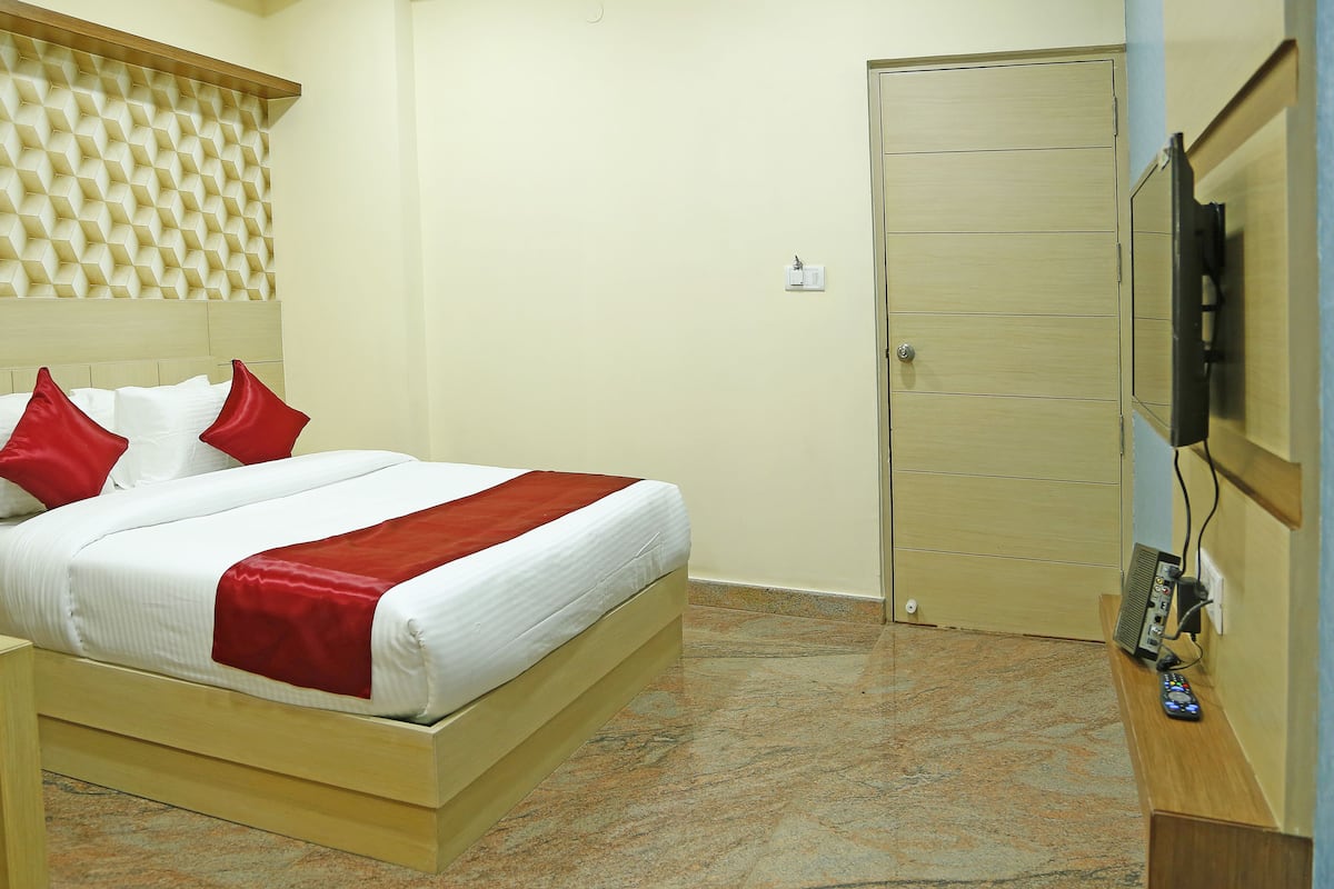 A hotel room with a bed, a bedside table, a TV, and a door.