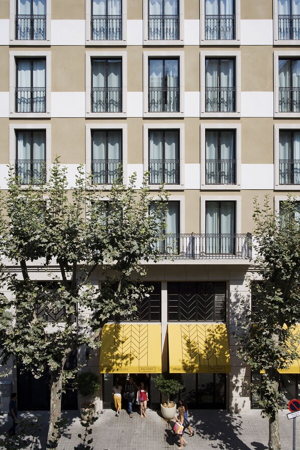 A multi-story building with a uniform facade, balconies with metal railings, and a ground-level entrance with a yellow awning. - Hotel Praktik Bakery (Barcelona)