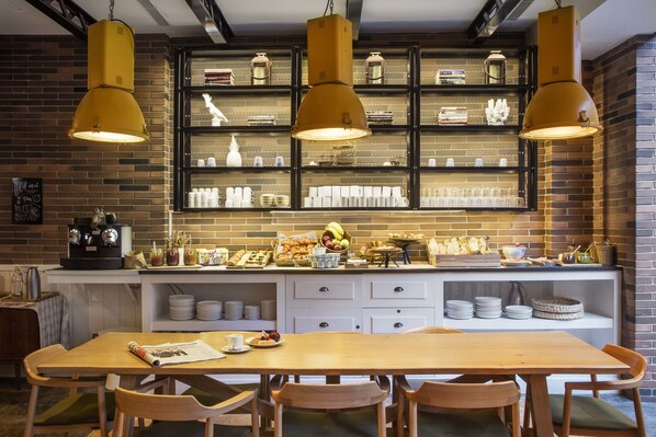 A cozy cafe with a brick wall, wooden tables, and hanging yellow pendant lights.