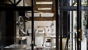 Una cocina con un chef preparando alimentos, un horno industrial grande y una vitrina con cestas.