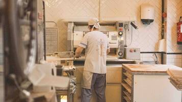 Una cocina con un chef preparando alimentos, equipada con equipos industriales y un salpicadero de azulejos.