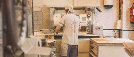 A kitchen with a chef preparing food, equipped with industrial appliances and a tiled backsplash.