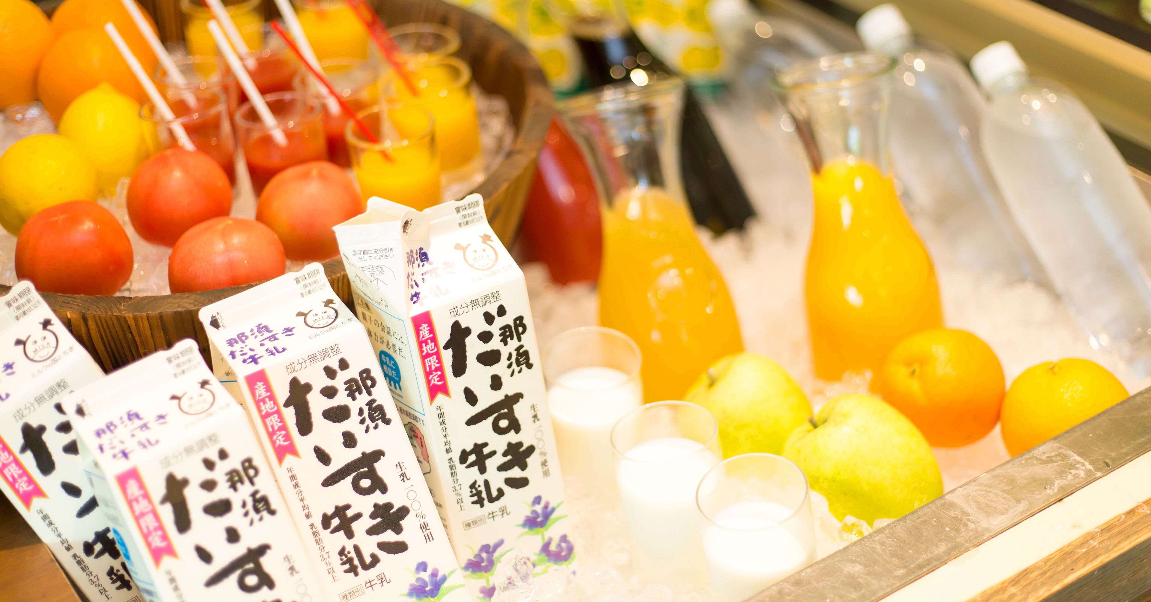 A display of beverages and fruits, including juice cartons and bottles, on a tray.