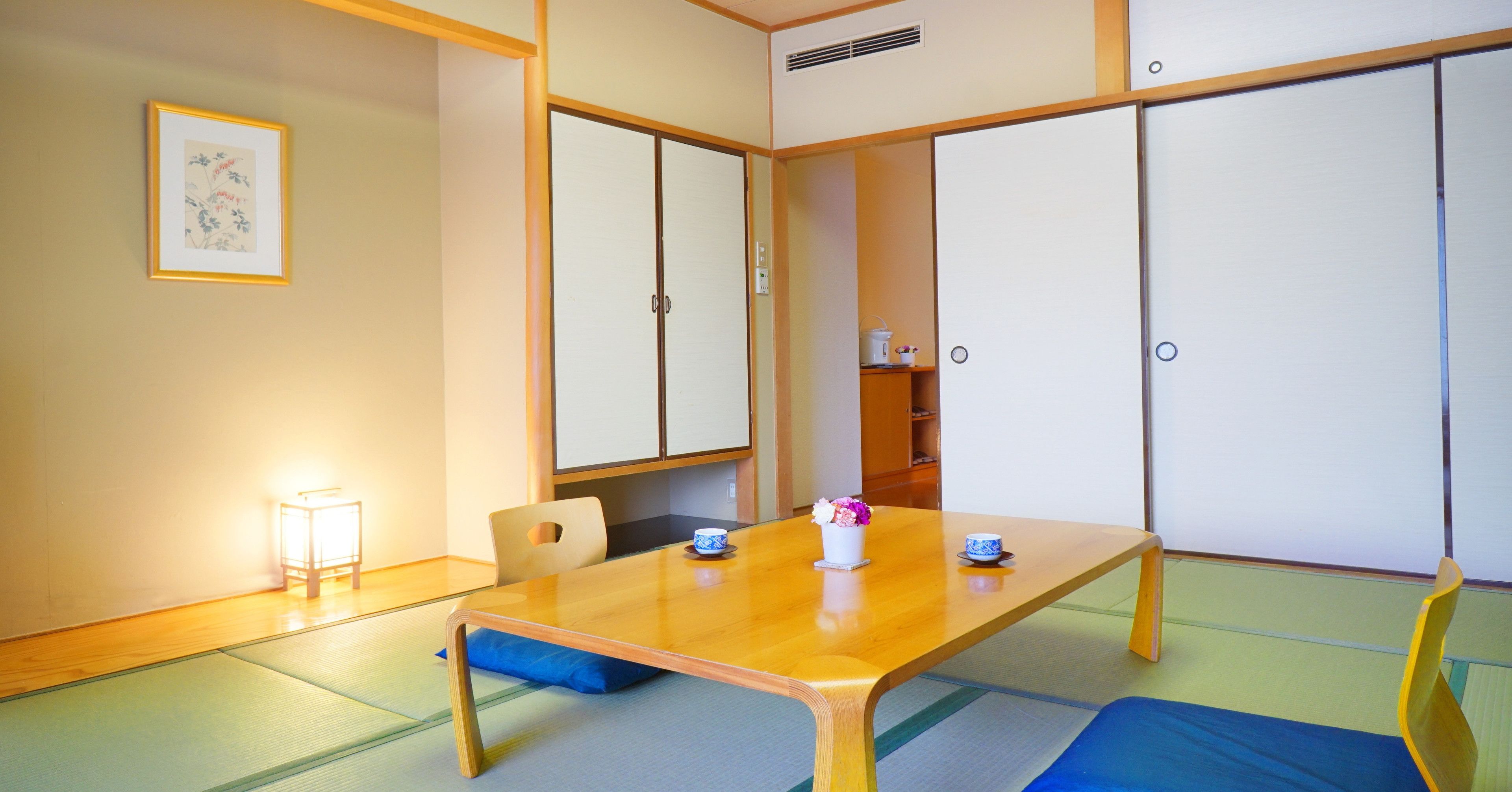 A traditional Japanese room with tatami flooring, a low wooden table, and shoji screens.