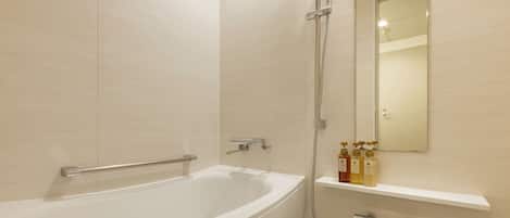 Un baño moderno con una bañera independiente, zona de ducha y un espejo sobre un estante con artículos de aseo.