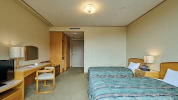 A hotel room with a bed, a desk with a chair, a television, and a lamp.