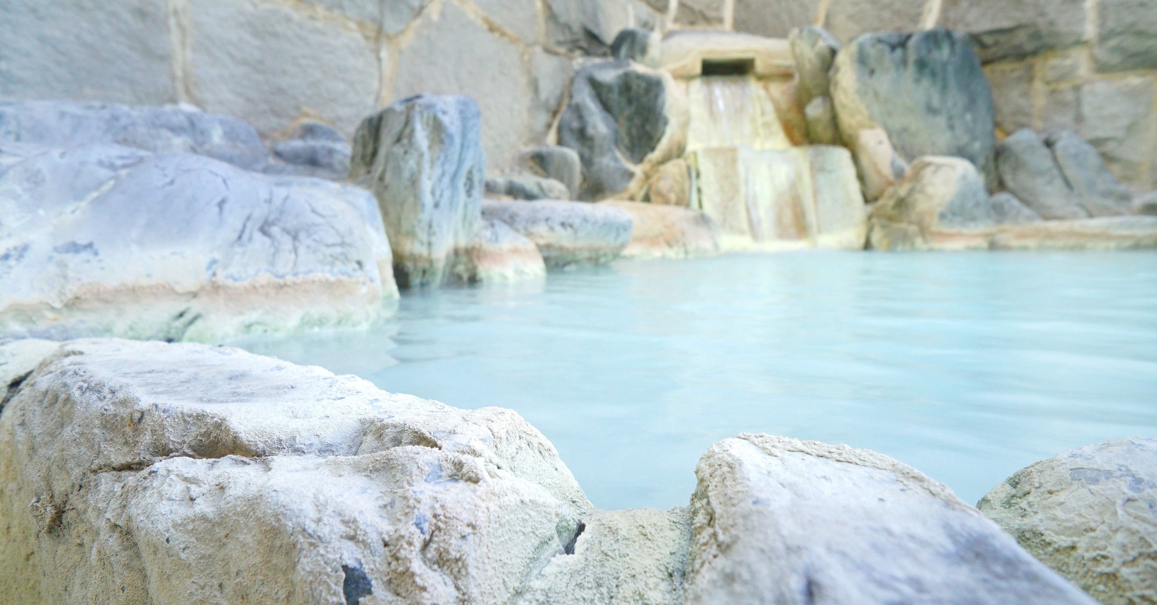 A natural hot spring with large rocks and a cascading water feature.