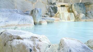 A natural hot spring with large rocks and a cascading water feature.