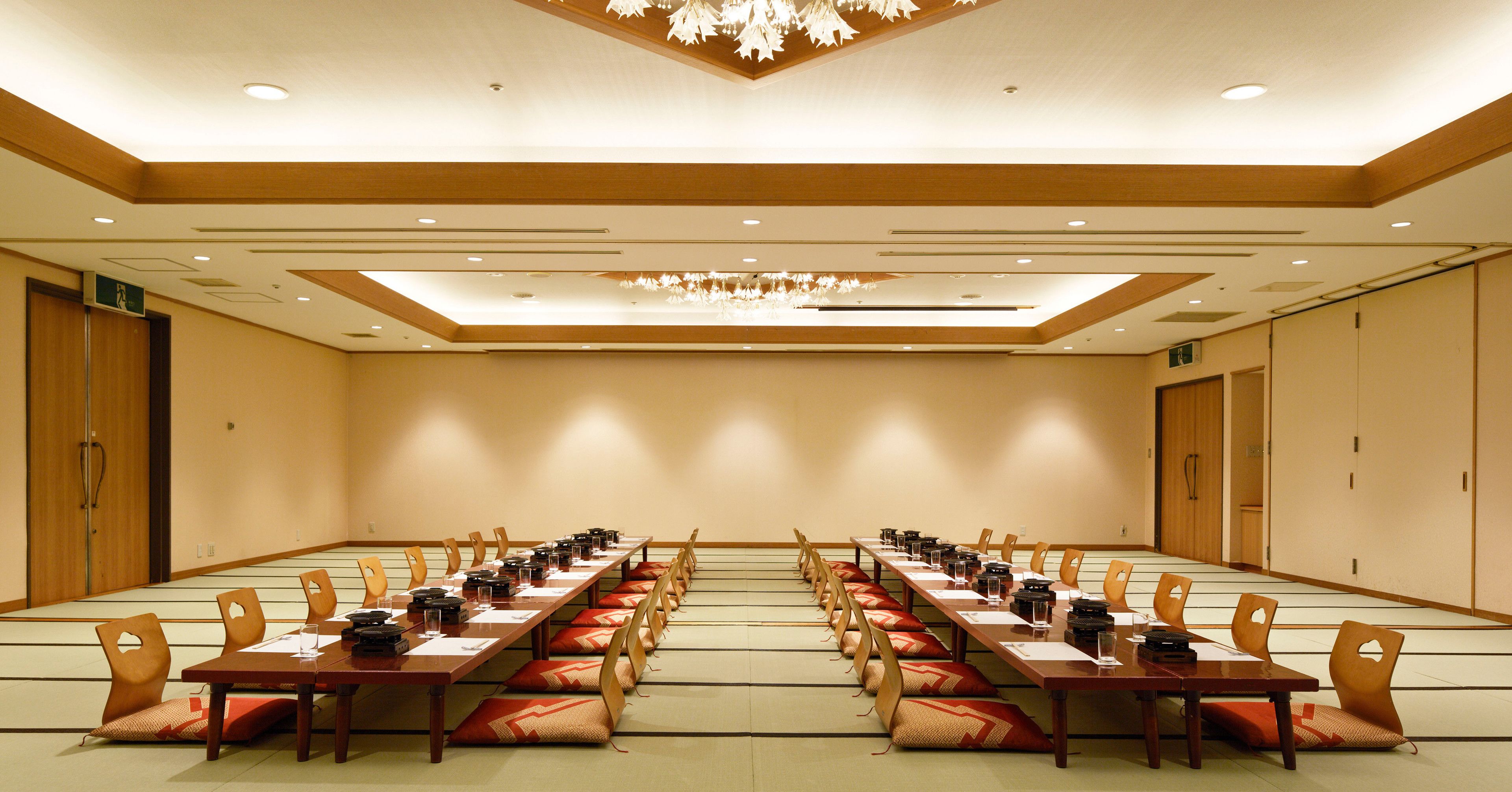 Une salle de conférence avec une longue table, des chaises et un lustre au plafond.