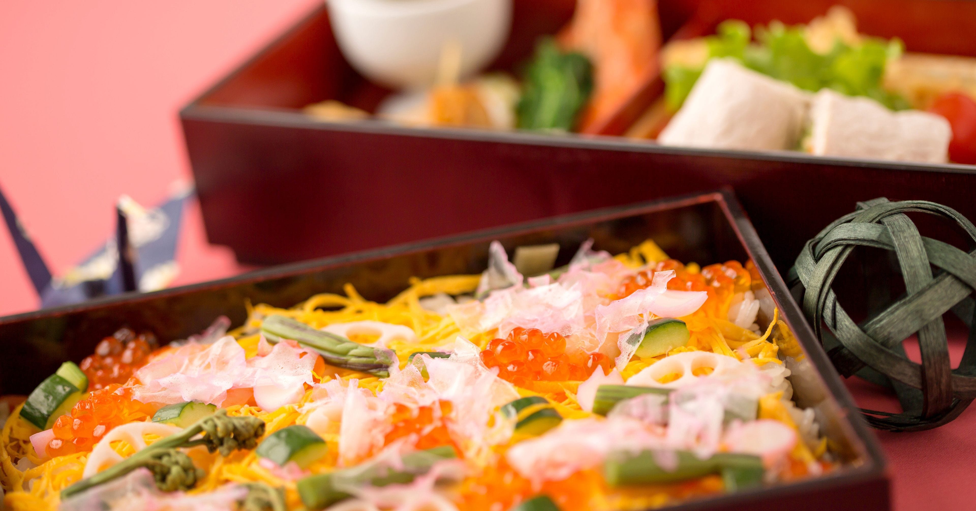 A variety of dishes including sushi and sashimi, served in a traditional wooden box.
