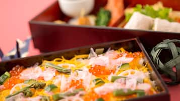 A variety of dishes including sushi and sashimi, served in a traditional wooden box.
