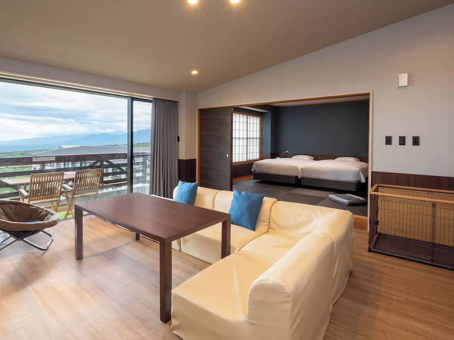 Quarto de hotel moderno com varanda, um sofá, uma mesa e uma cama.