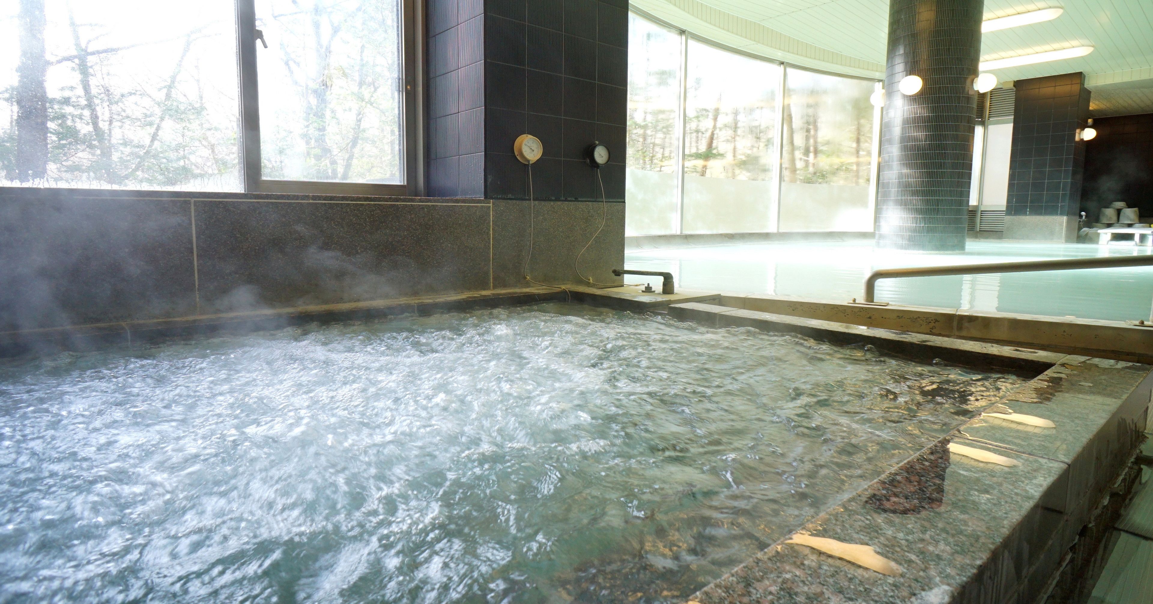 A hot tub area with a view of trees outside, a clock on the wall, and a steam vent.