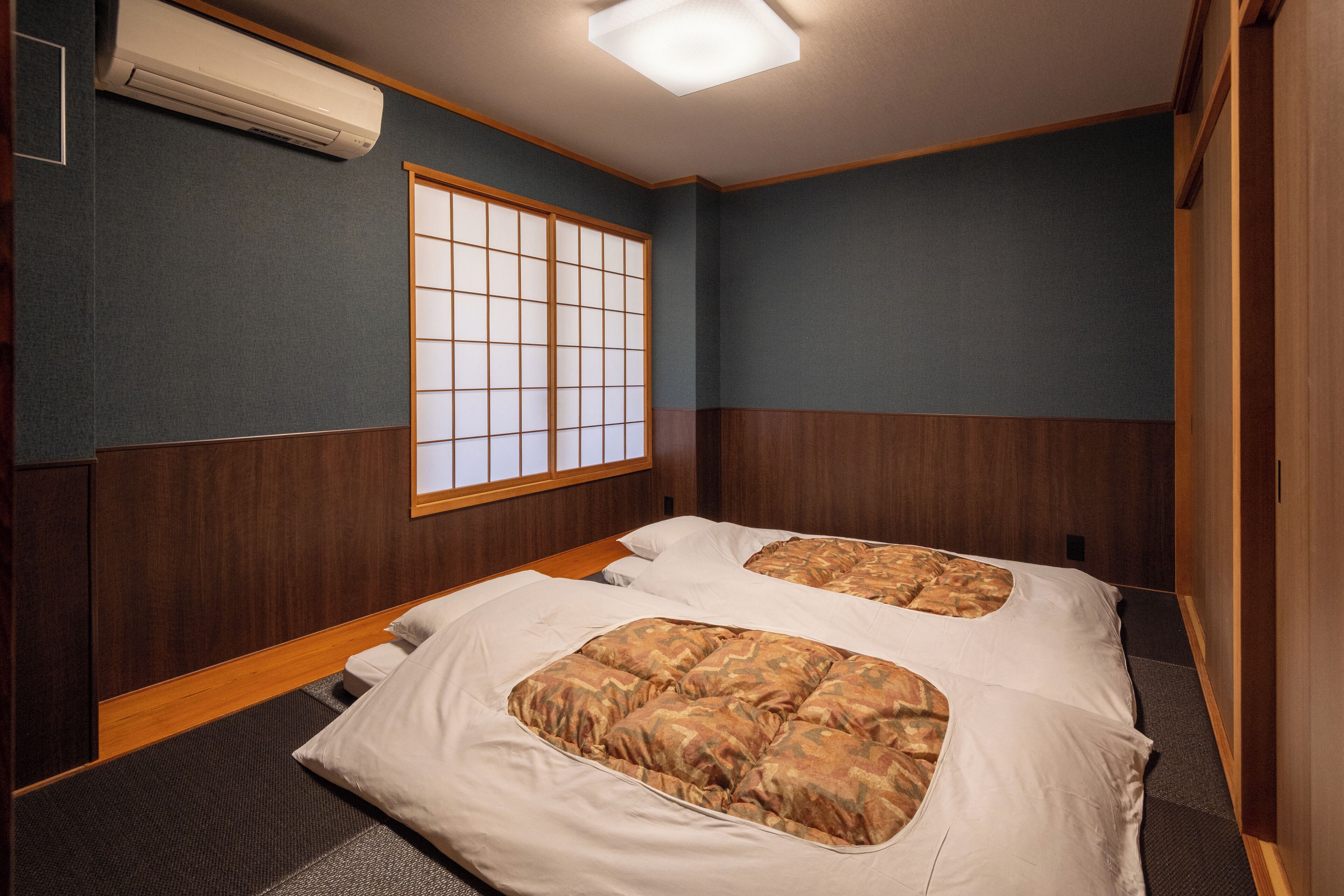 A hotel room with two beds, a shoji screen, and a wooden floor.