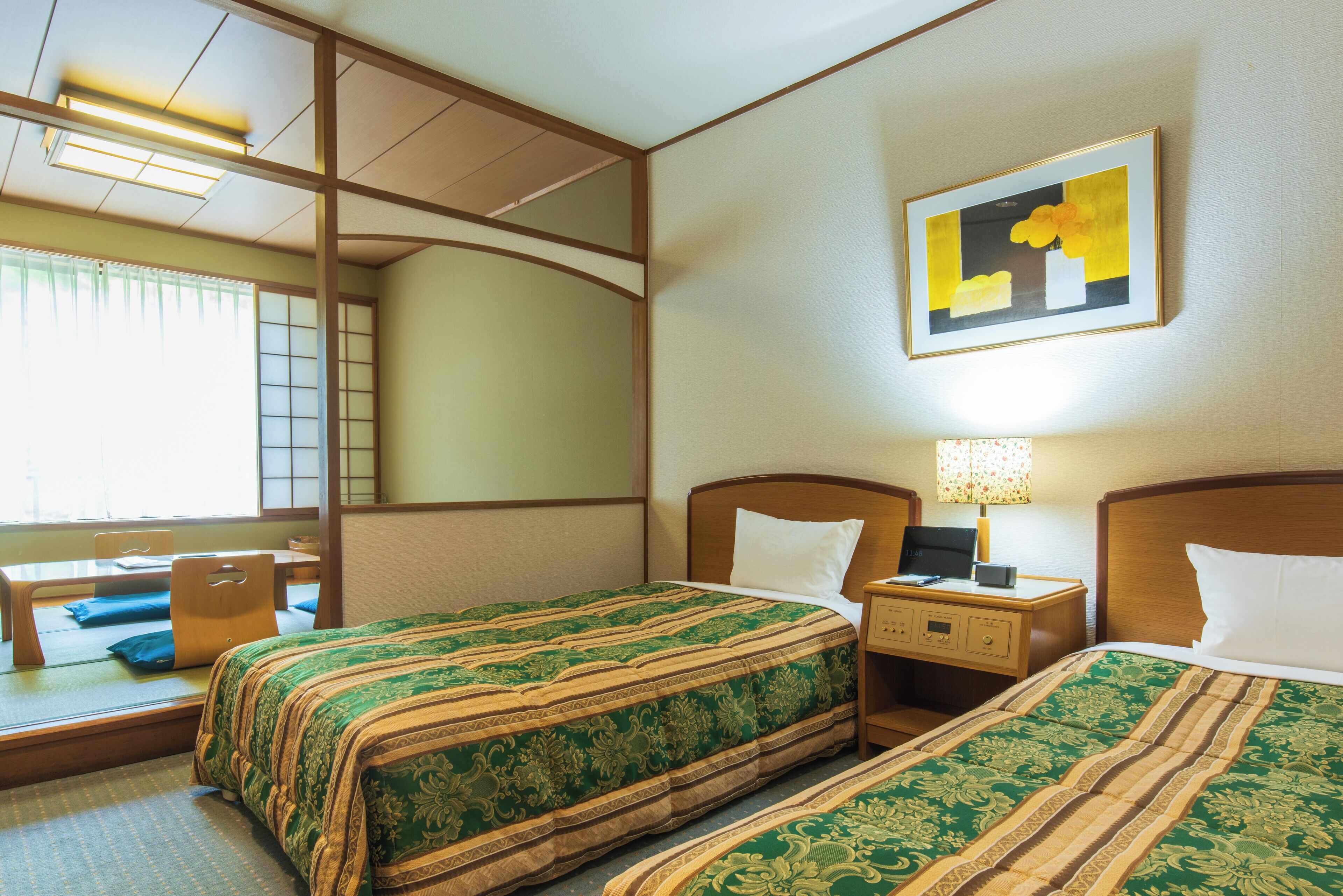 A hotel room with two beds, a desk, and a chair.