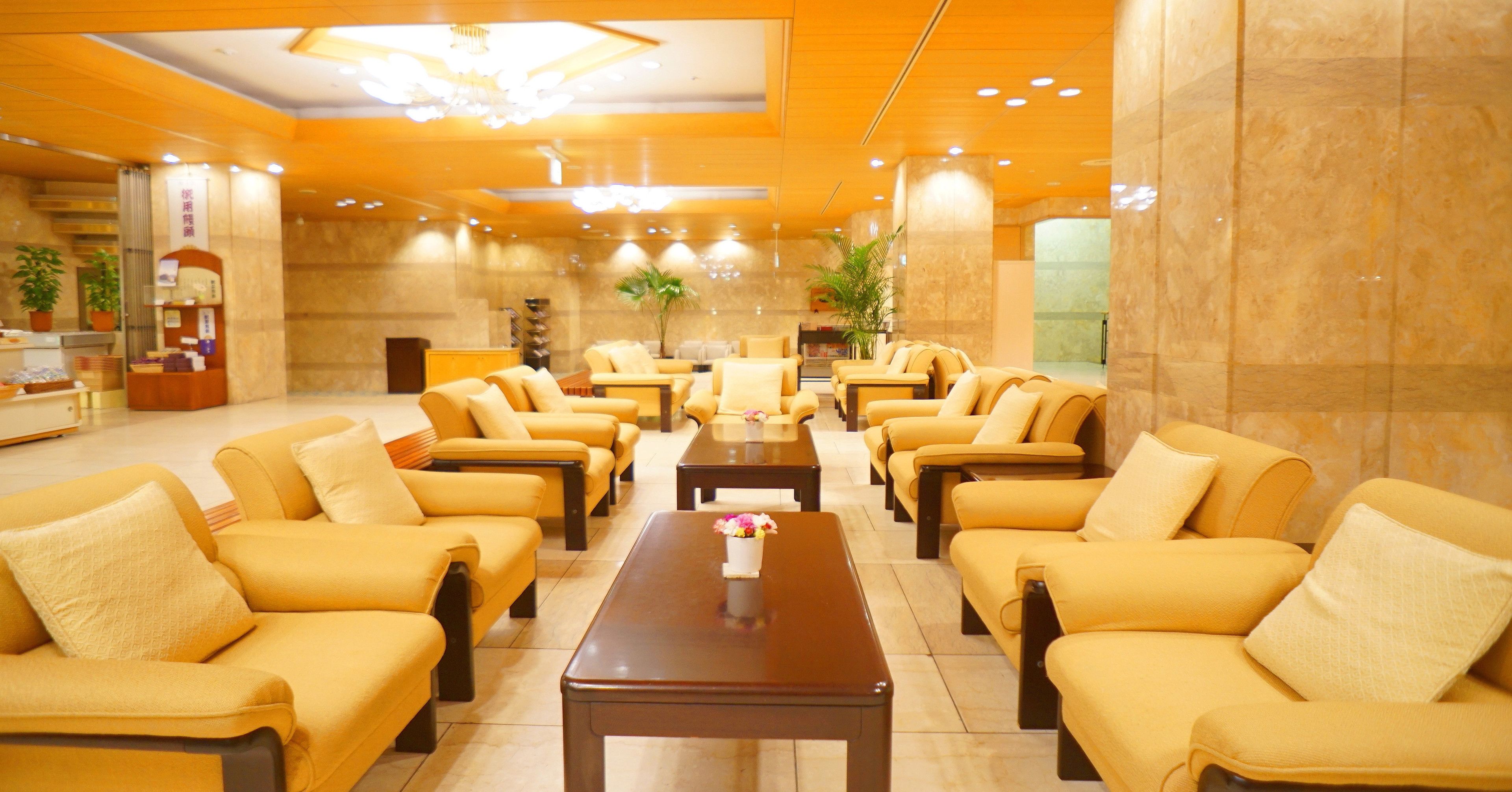 A hotel lobby with multiple seating areas, a reception desk, and a decorative plant.