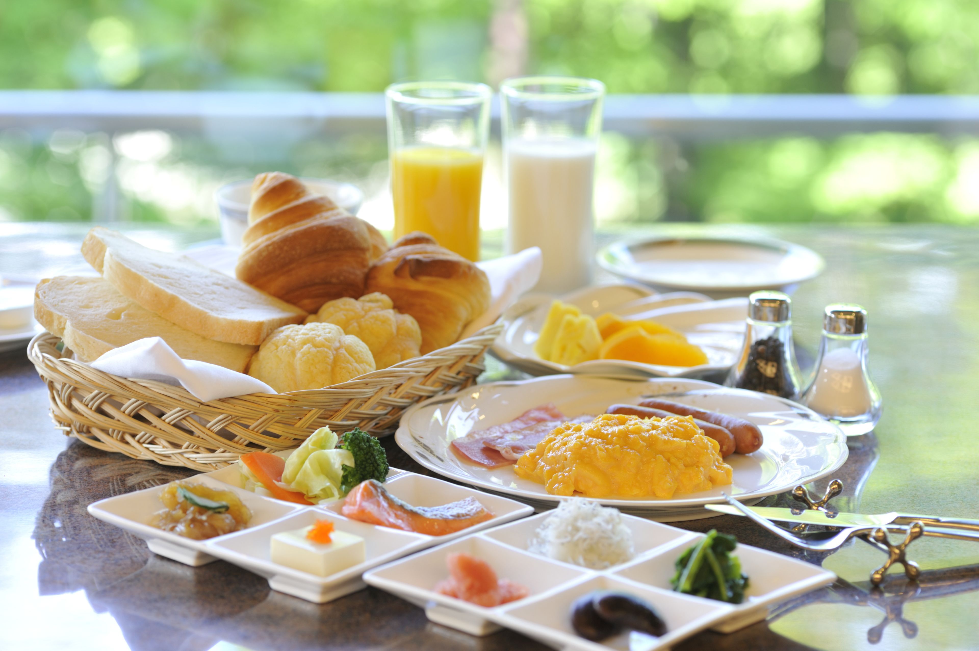 Une table de petit-déjeuner avec divers aliments et boissons, notamment du pain, des œufs et du jus de fruits.
