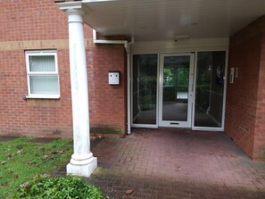 A brick building with a white column, a window, and a door with glass panels. - Genesis Home Serviced Apartment (Coventry)