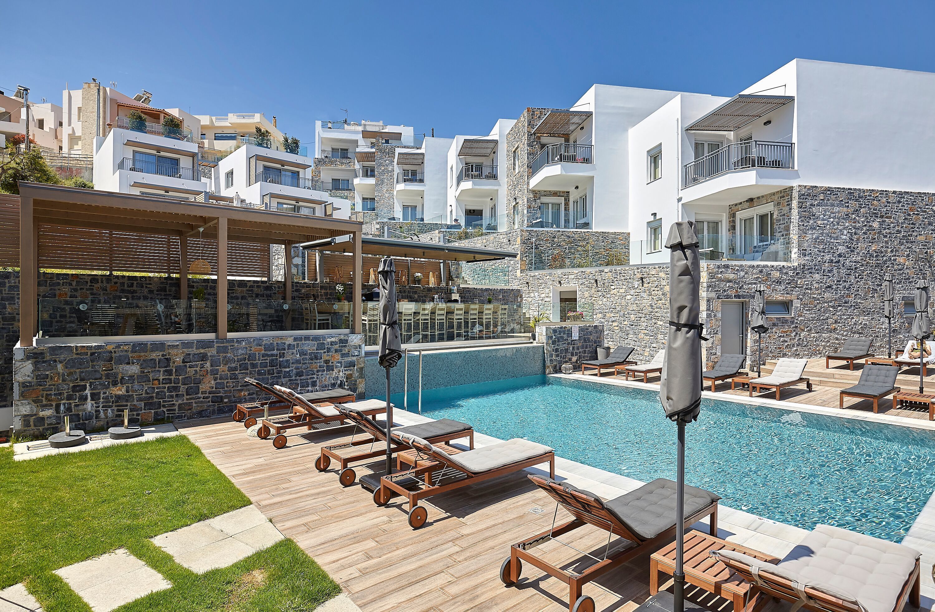A modern resort with a swimming pool, lounge chairs, and a bar area.