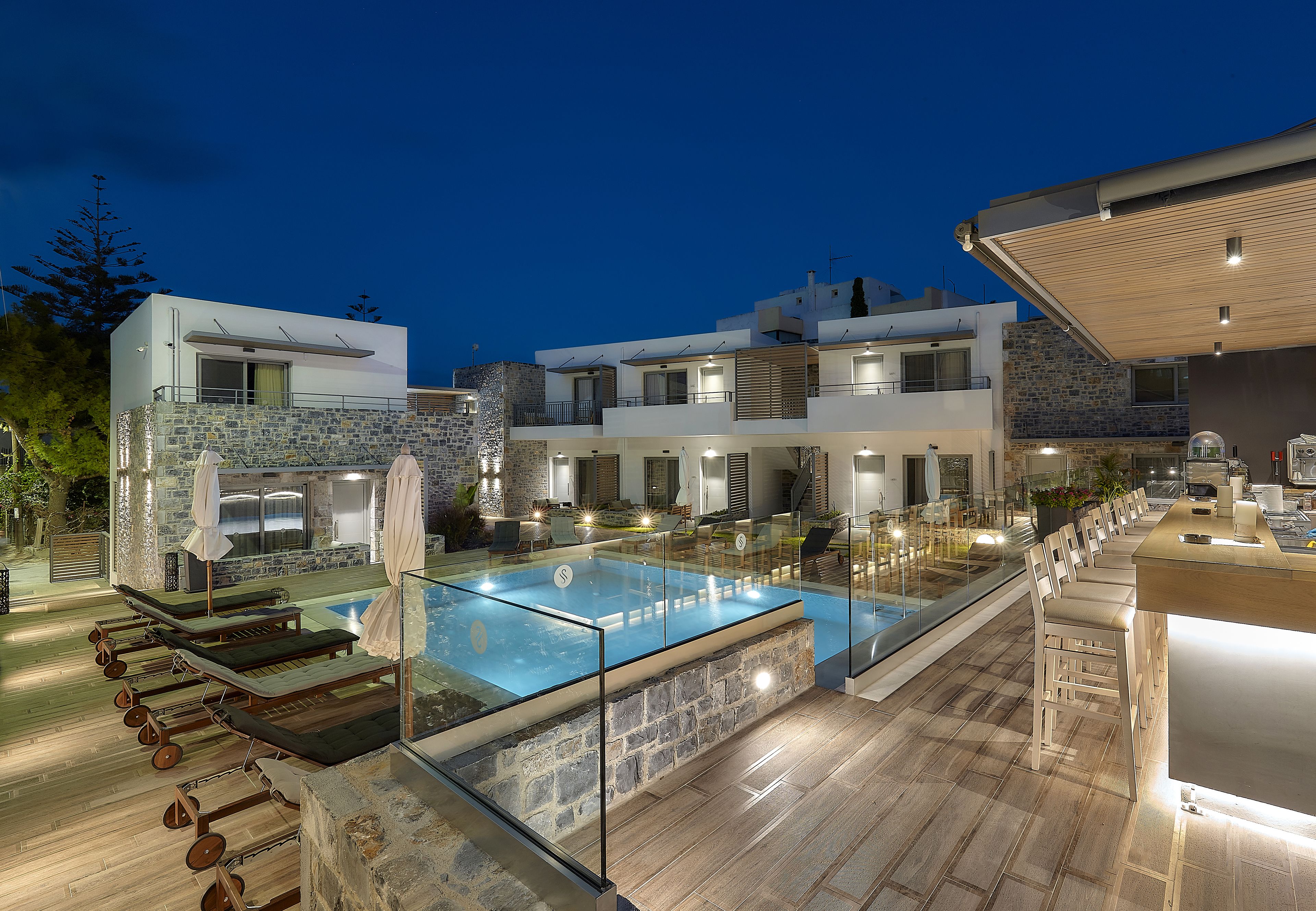 Un espace piscine extérieur moderne, doté de chaises longues et d’un bar.
