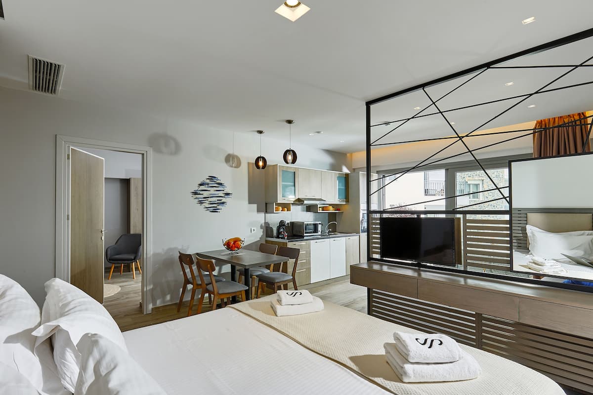 Moderni hotellihuone, jossa on sänky, ruokailutila ja pieni keittiönurkkaus.