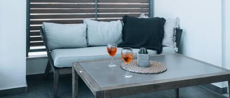 A modern living room with a grey sofa, two glasses of red wine, and a small cactus on a woven coaster.