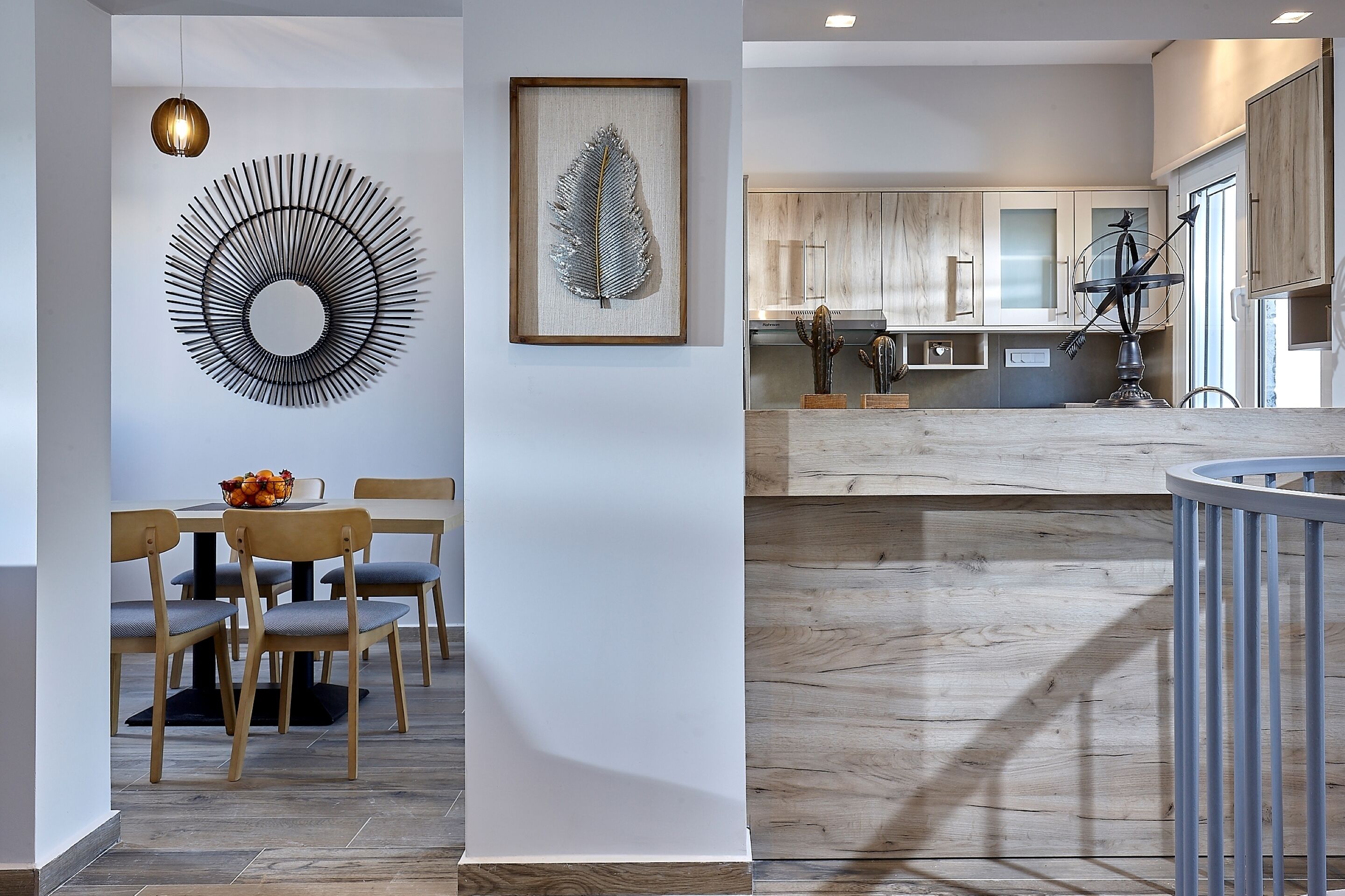 Una cocina moderna con armarios de madera, un comedor con mesa y sillas redondas, y una gran obra de arte en la pared.