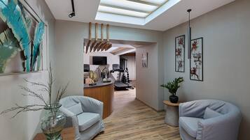 Un intérieur moderne doté d’une verrière, d’un comptoir d’accueil, d’un téléviseur, d’équipements de musculation et de deux espaces de détente.