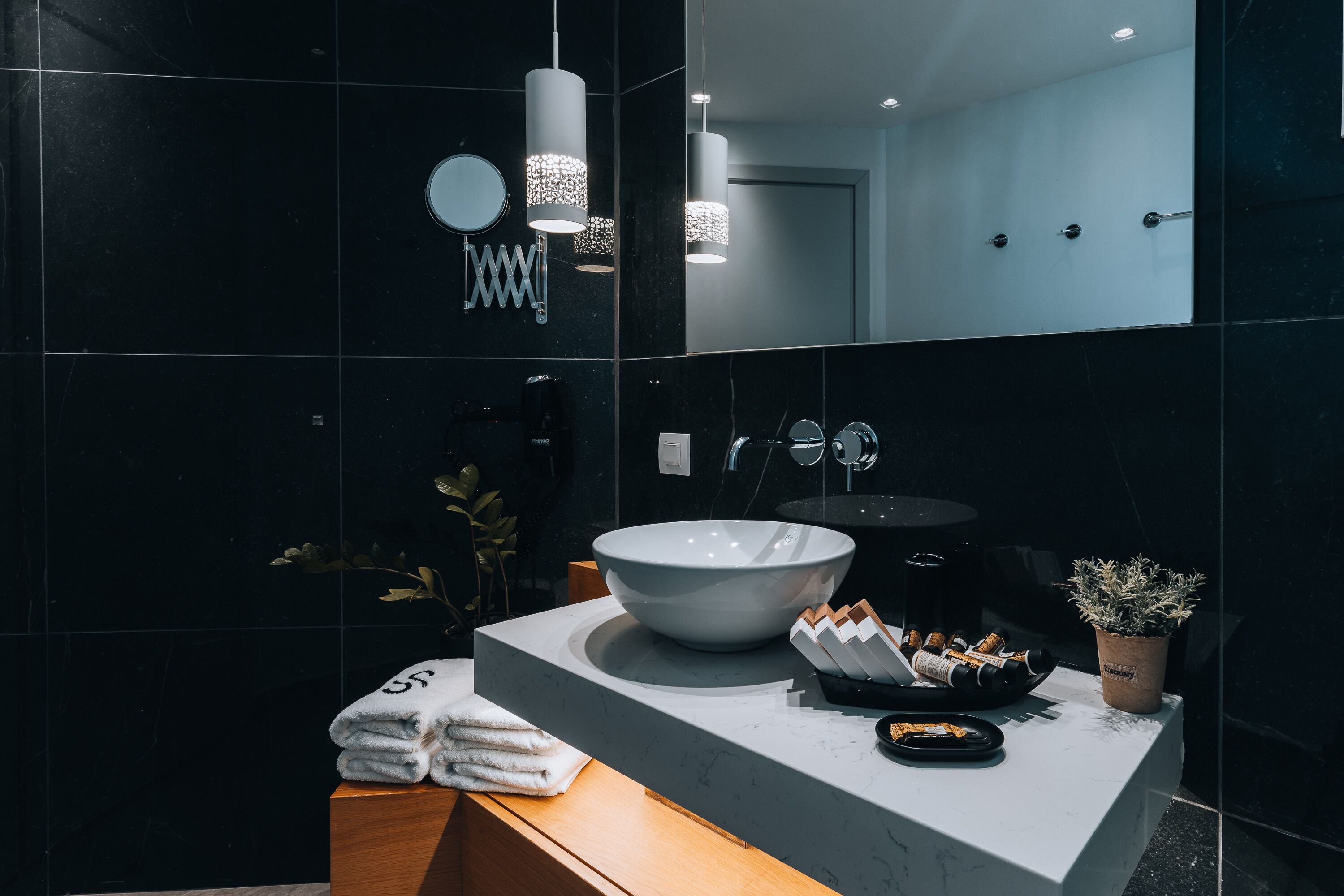 A modern bathroom with a large white sink, a mirror, and a towel rack.