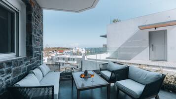 A modern outdoor seating area with a stone wall, a glass railing, and a view of the cityscape.