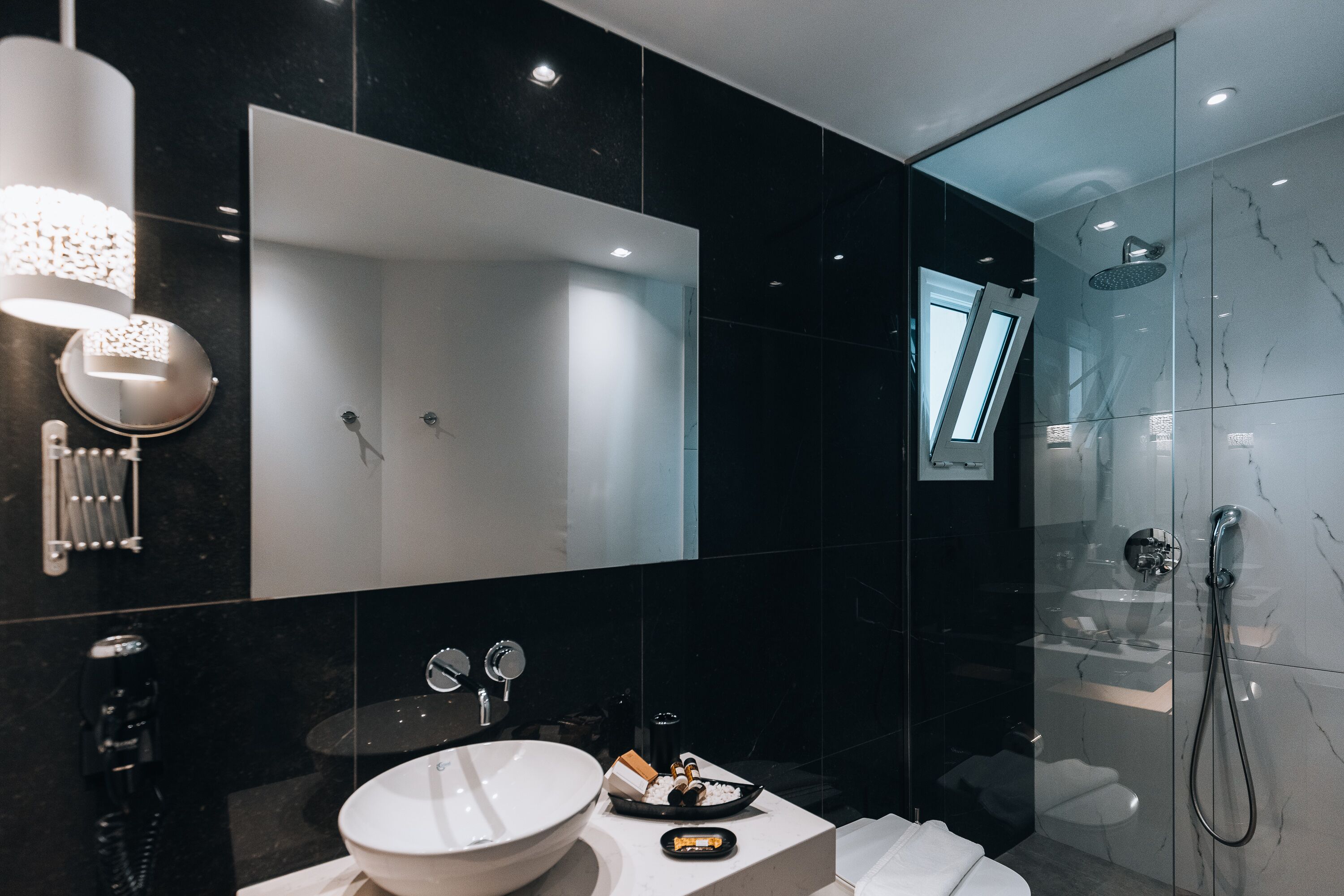 Un baño moderno con un espejo grande, un lavabo redondo y una zona de ducha.