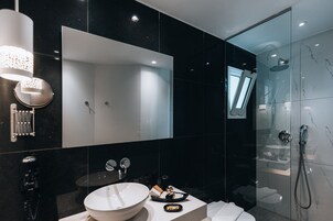 Un baño moderno con un espejo grande, un lavabo redondo y una zona de ducha.